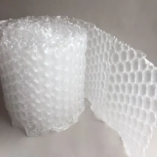 Roll of clear bubble wrap packing material with a partially unrolled sheet on a plain light background
