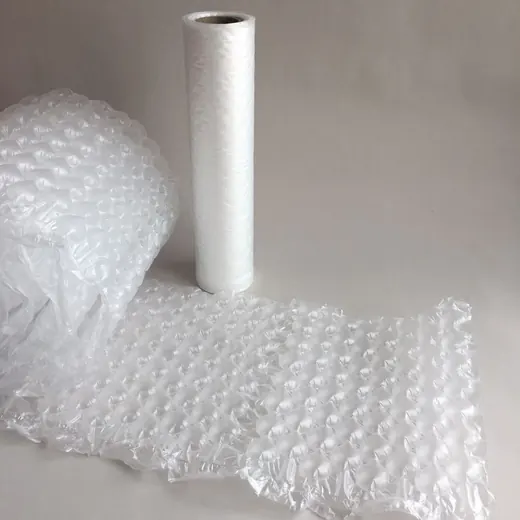 Rolls of transparent bubble wrap on a neutral background, one standing upright and one unrolled into a flat sheet
