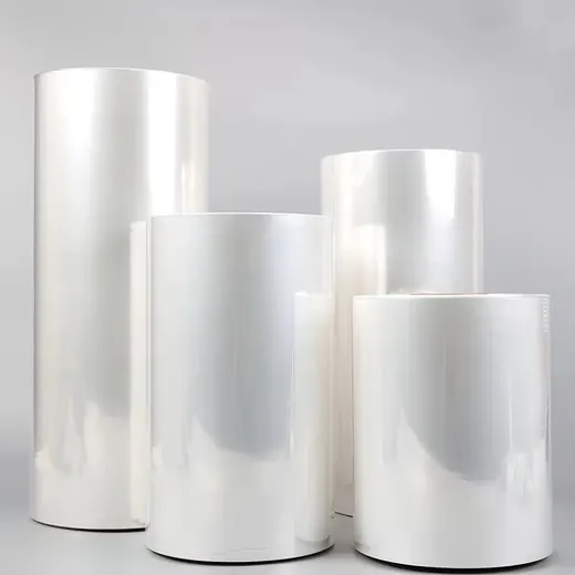 Glossy clear plastic film rolls of various heights standing on a plain light gray background.