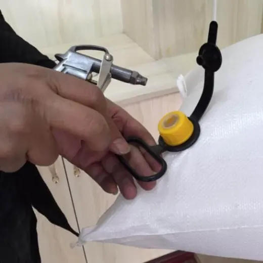 Person handling the yellow-capped inlet spout and loop of a white woven bulk bag