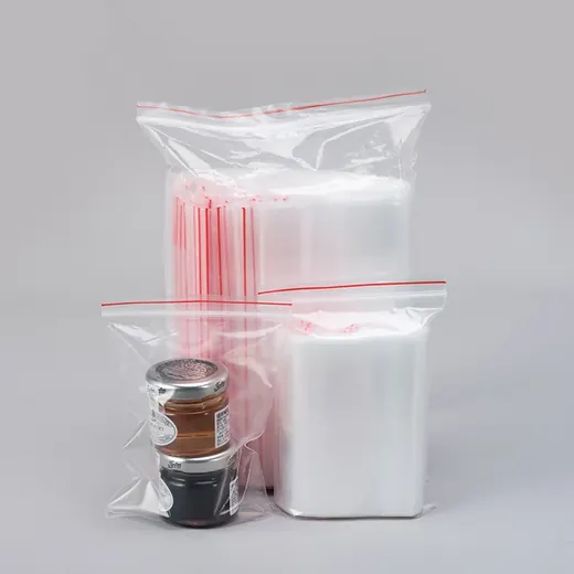 Clear resealable zip bags with red seals, some holding small jars, arranged on a plain gray background