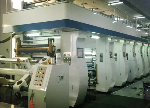 Large white industrial multi-station printing machine with control panels on a factory floor