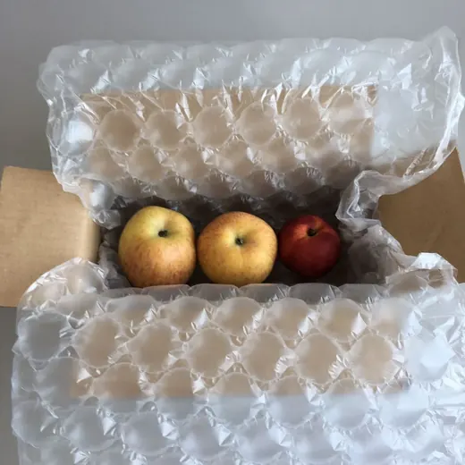 Air cushion packaging film lining a cardboard box filled with apples