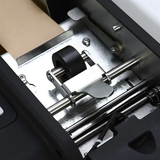 Close-up of a label printer's internal mechanism with black roller, metal plate, guide rails and