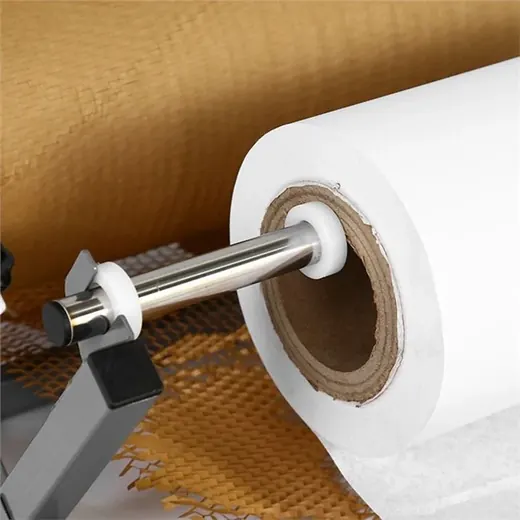 A roll of white material is mounted on a metal spindle on a machine, with brown and patterned rolls in the background.
