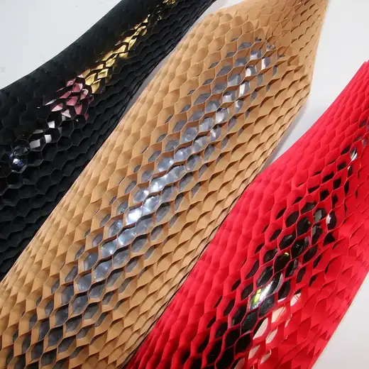 Close-up of three stretched honeycomb paper wrap sleeves in black, kraft tan, and red