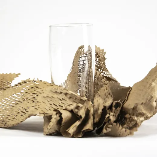 Clear glass tumbler nestled in crumpled perforated kraft honey