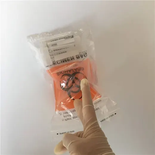 Gloved hand pointing at a plastic biohazard specimen bag with orange pouch on white background