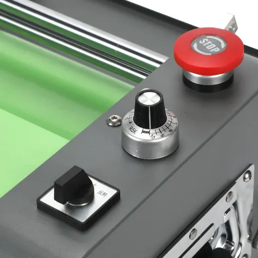 Close up of machine control panel with red emergency stop button and black rotary dial