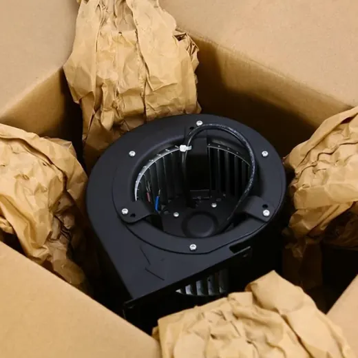 Black centrifugal blower fan nestled inside a cardboard box with crumpled paper packing material.