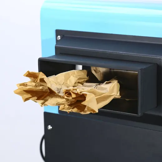 A close-up of a blue and black machine dispensing crumpled brown packing paper.