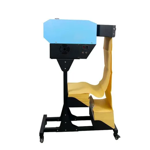 Industrial paper cutting machine with a blue housing and black stand, loaded with a stack of yellow paper.