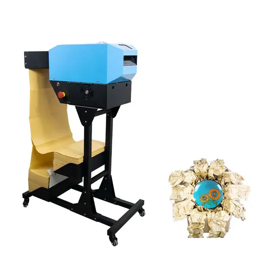 Industrial paper shredding machine on a stand next to a bin of crumpled paper.