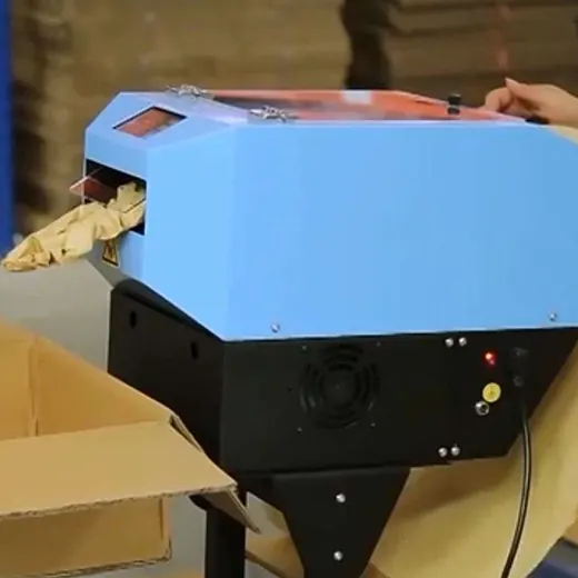 Blue paper void fill machine dispensing cushioning paper into a cardboard box, operated by a hand