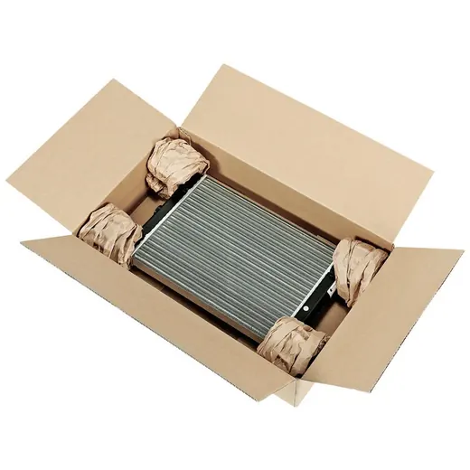 Heat exchanger cushioned with crumpled paper inside an open cardboard shipping box on a white background