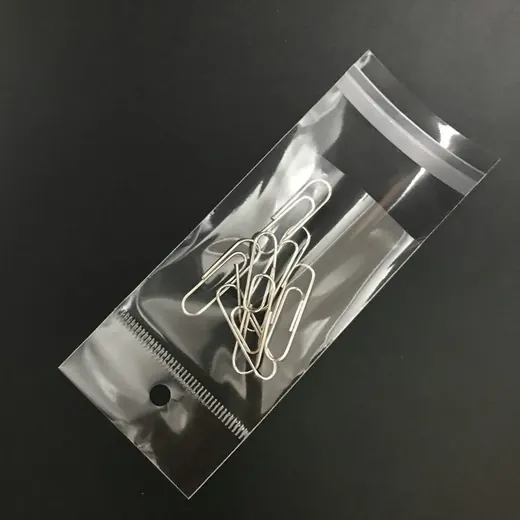 Silver paper clips inside a clear plastic ziplock bag on a dark background