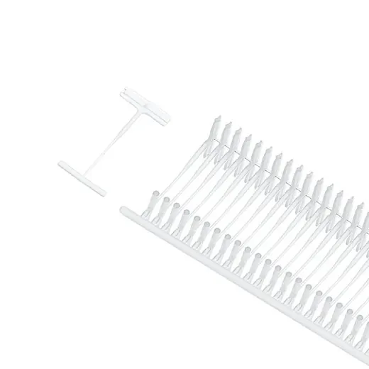 Strip of white plastic T-shaped tag fasteners on a runner, with one loose fastener at left, white background