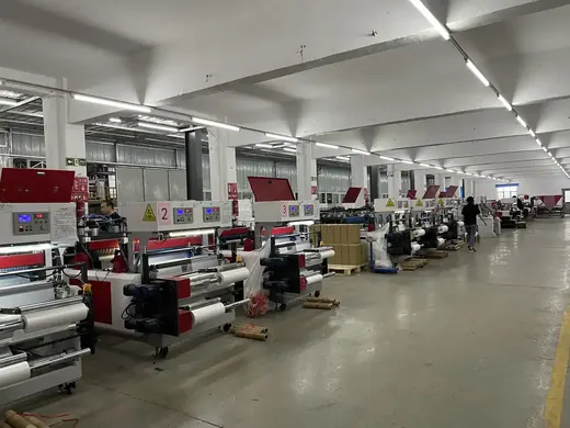 Wide view of a factory floor with rows of numbered industrial machines and a worker walking in the distance