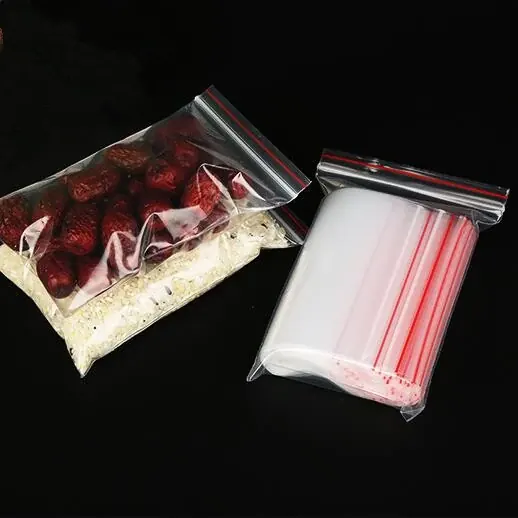 Two clear plastic ziplock bags containing dried dates and straws, stacked over a white granular substance on a black background.