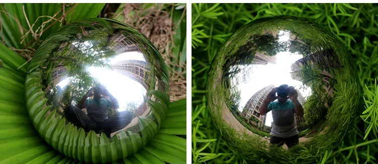 A reflective chrome sphere resting on green leaves, showing a distorted reflection of a person taking a picture.