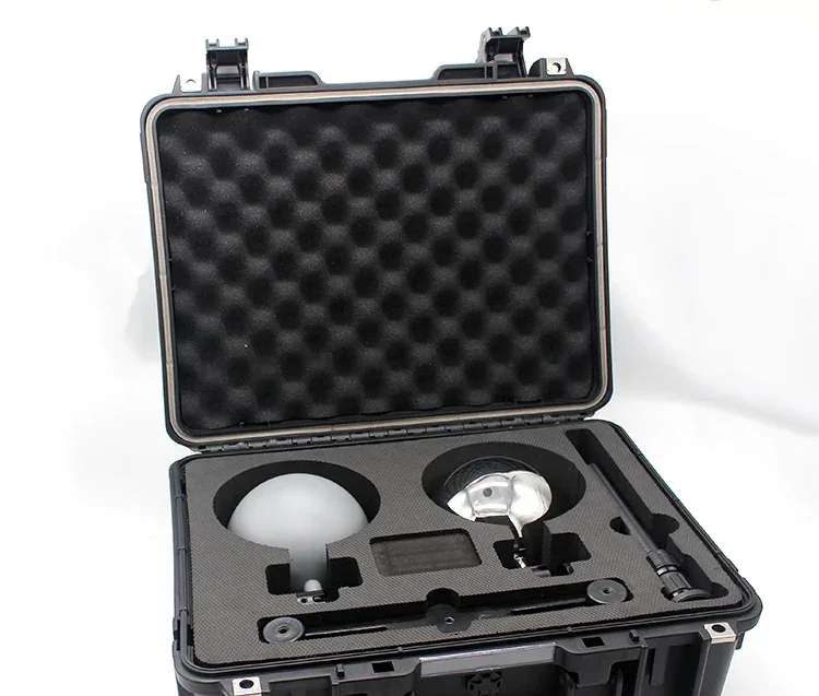 Open black hard case with foam insert holding a glowing spherical lamp and metal accessories