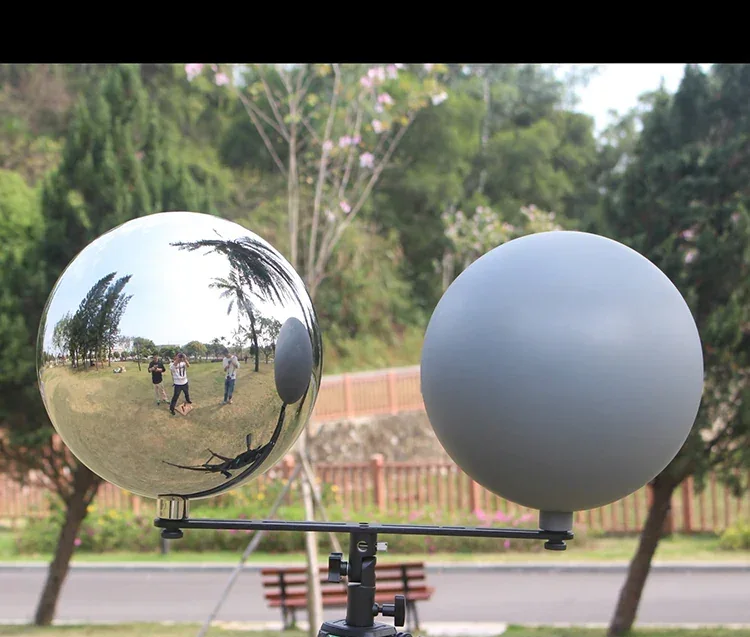 Side-by-side comparison of a polished reflective sphere and a matte gray sphere mounted on a stand.