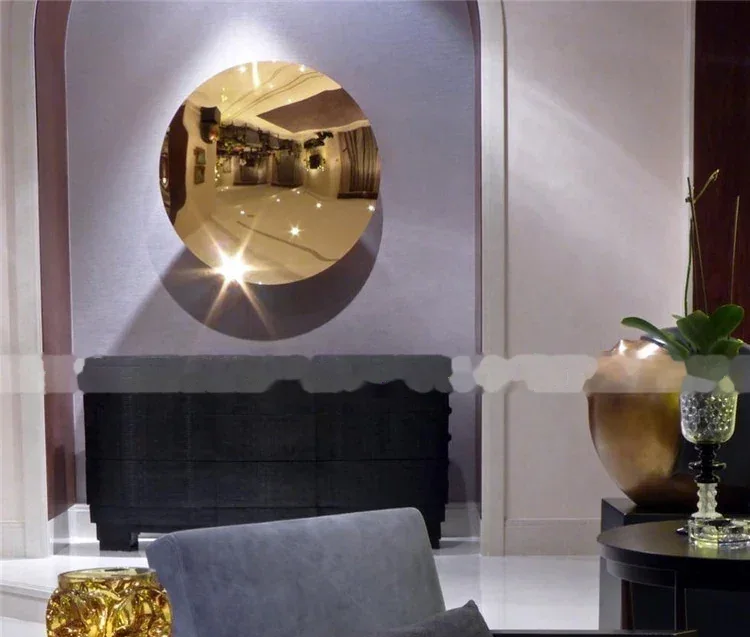 A large, circular, gold-colored mirror mounted on a wall, reflecting a hotel lobby.