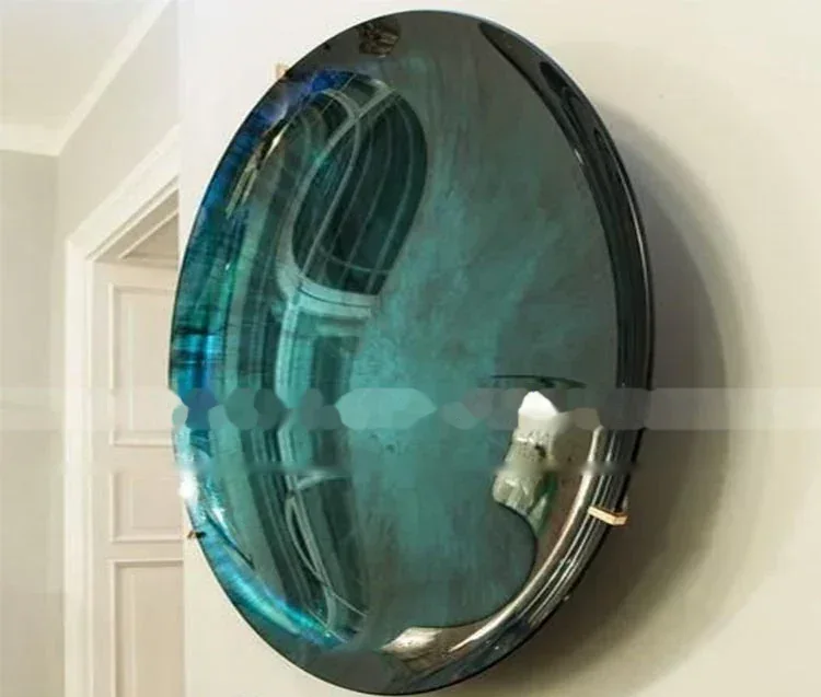 Round tinted convex mirror with teal-blue reflective glass mounted on a white interior wall