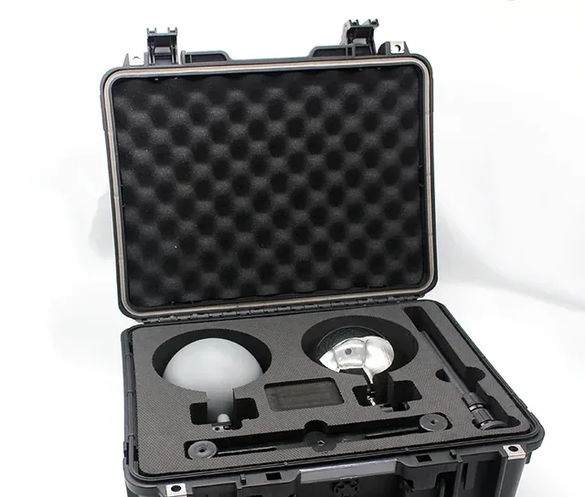 Open black hard case with foam insert holding a glowing spherical lamp and metal accessories
