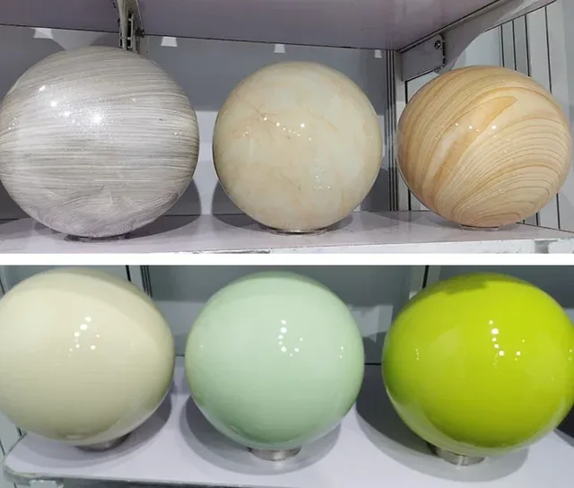 Six glossy decorative spheres on white shelves: three marbled designs above, three solid cream, mint and chartreuse balls below