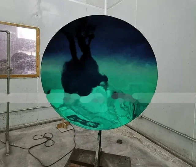 Large circular silicon wafer standing on a metal stand in a room.