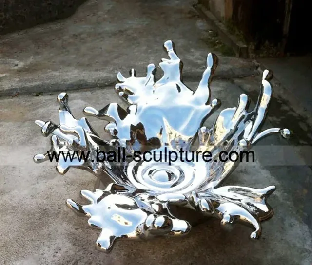 Polished stainless steel water splash sculpture displayed on outdoor concrete pavement