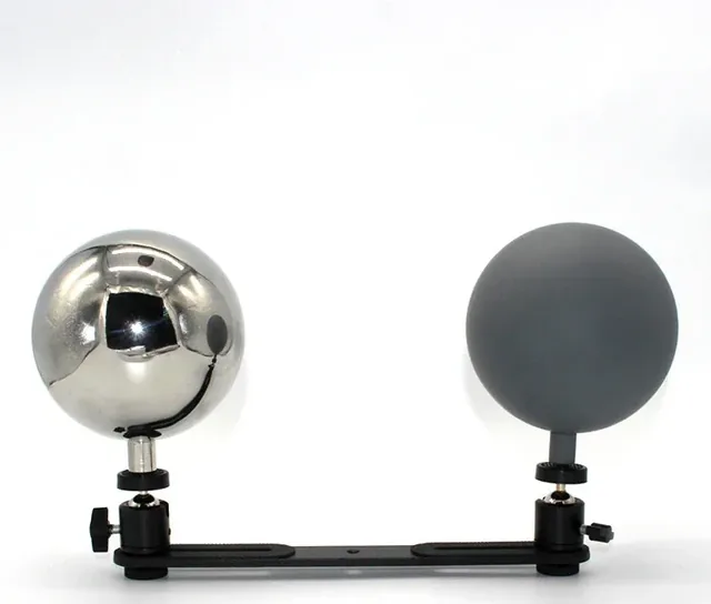 Polished chrome sphere and matte grey sphere mounted on adjustable black clamps on a horizontal bar