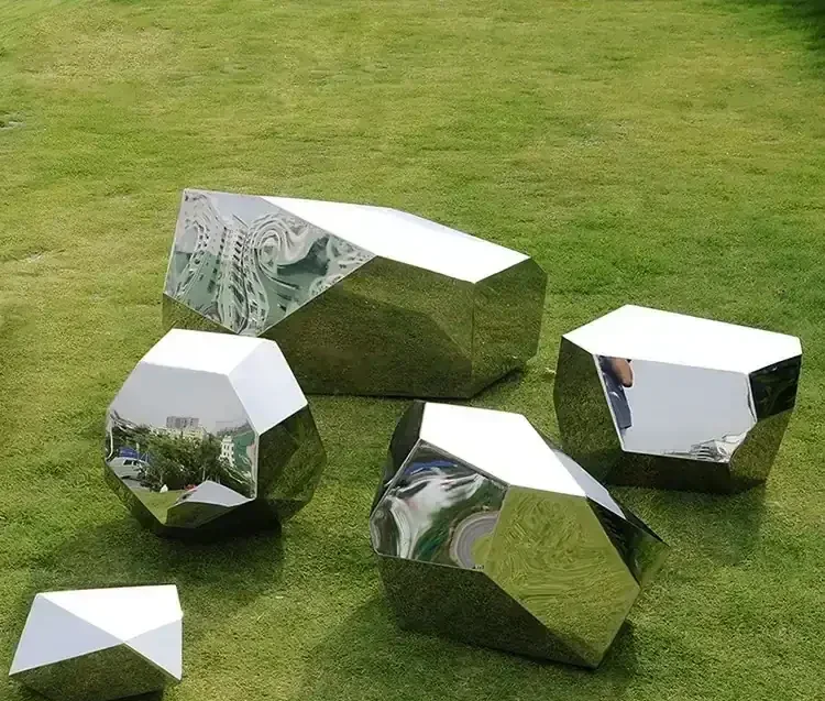 Faceted stainless steel geometric sculptures arranged on a green lawn