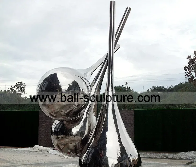 Large mirror-polished stainless steel droplet sculpture with tall vertical stems displayed outdoors