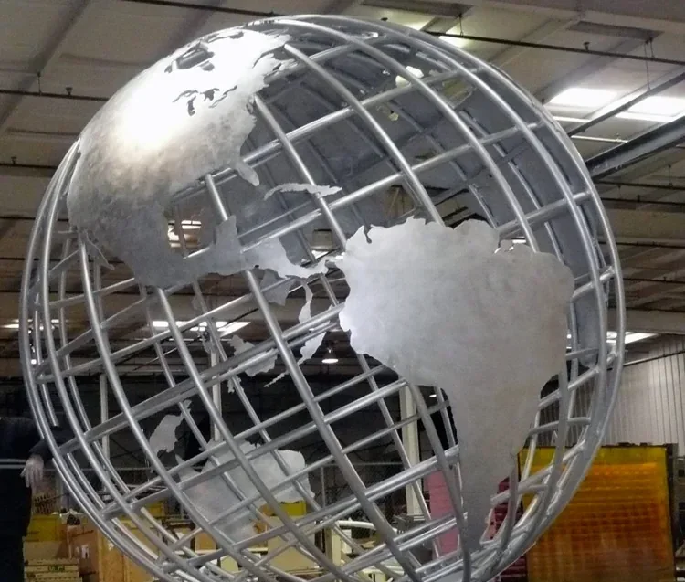 Large fabricated metal globe sculpture with steel continents inside an industrial workshop