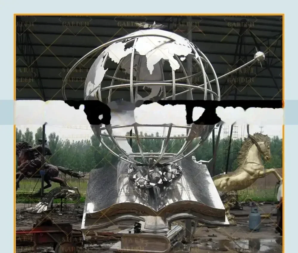 Large stainless steel sculpture of a globe resting on an open book