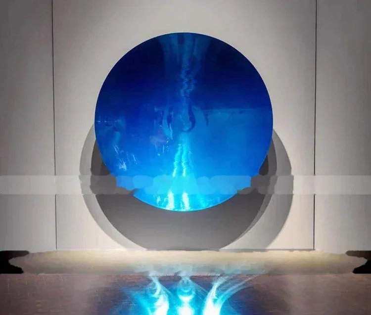 A view through a circular porthole window showing bright blue light from inside a large industrial furnace.