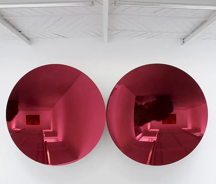 Two circular mirrors reflecting a room with pink lighting