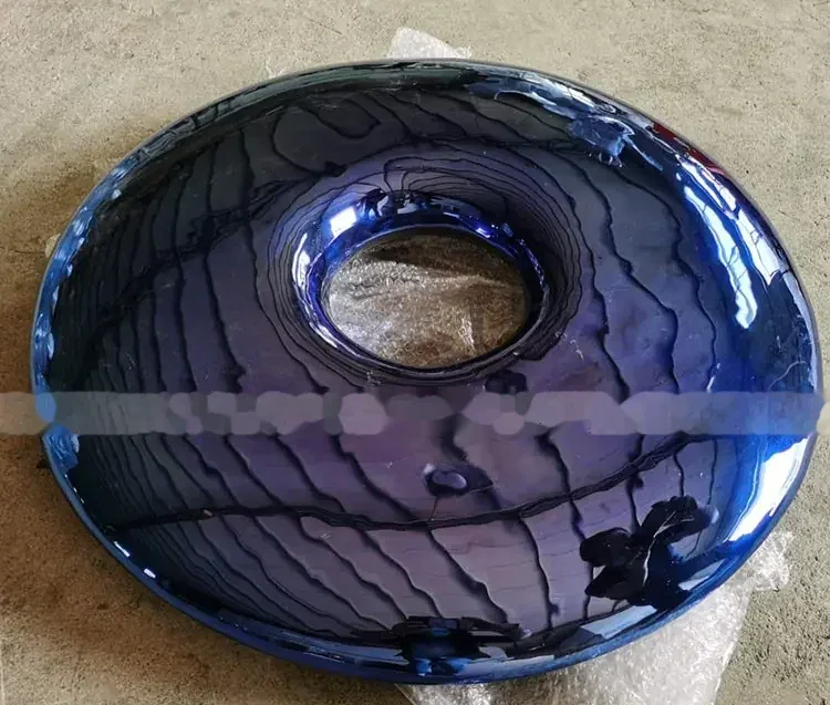 Glossy dark blue dome-shaped object with a central round opening, photographed on a bare concrete floor