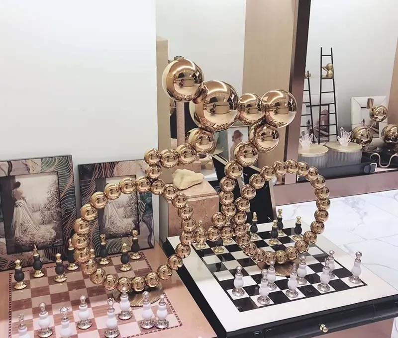 A decorative gold chess set with sculptural, bubble-like pieces on a checkered board.
