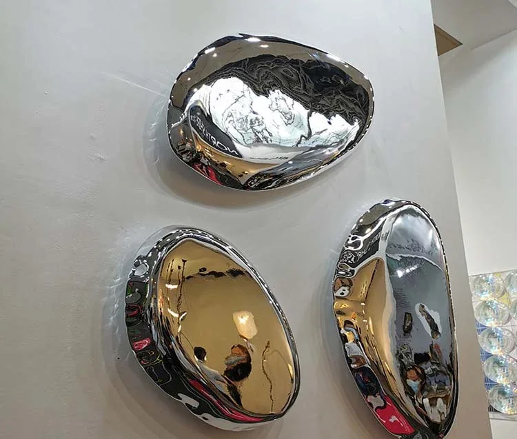 Three polished metallic organic-shaped trays mounted on a white wall