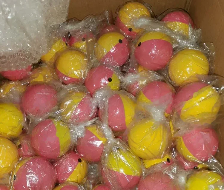 Cardboard box filled with pink and yellow two-tone balls individually wrapped in clear plastic bags, bubble wrap at top left