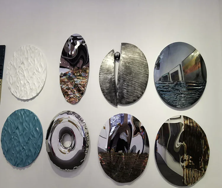 Decorative textured and polished stainless steel wall discs in varied finishes mounted on a white wall