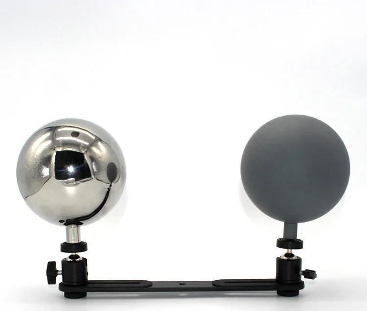 Polished chrome sphere and matte grey sphere mounted on adjustable black clamps on a horizontal bar
