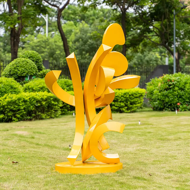 Yellow abstract metal sculpture standing on a circular base in a grassy park area.