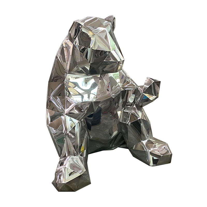 Geometric faceted bear sculpture in polished reflective metal, seated, on a white background