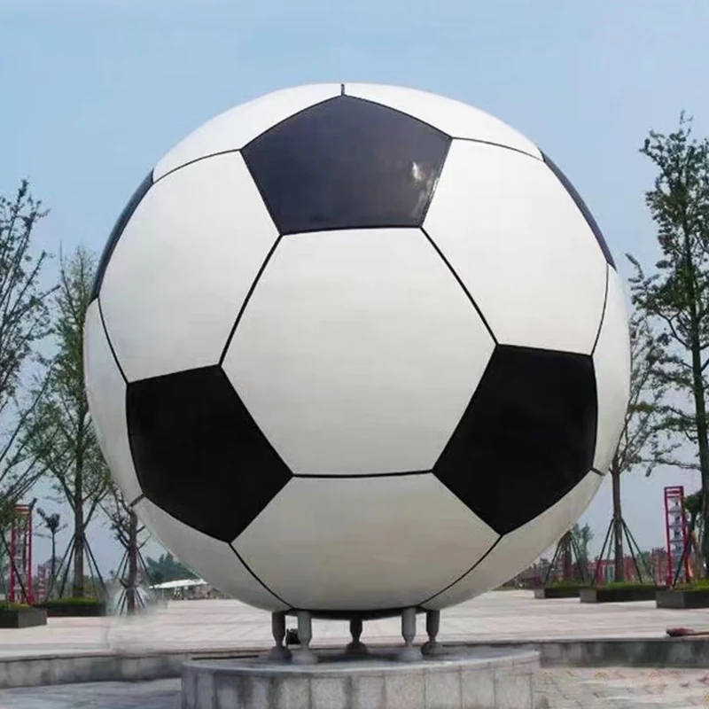 Stainless steel football sculpture painted black and white on a stone pedestal
