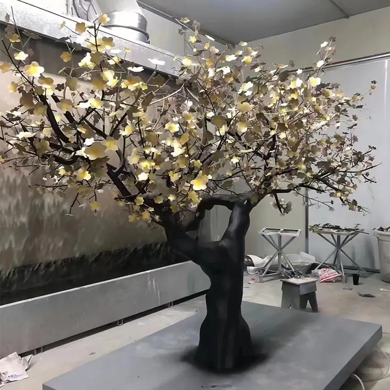 Metal blossom tree sculpture with dark trunk and gold leaves in the workshop