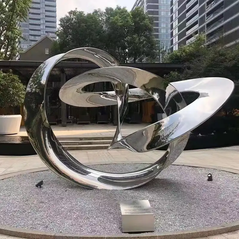 Mirror polished stainless steel interlocking rings sculpture on a plaza plinth